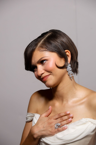 Zendaya poses at a premiere wearing a white gown and neutral milky manicure.